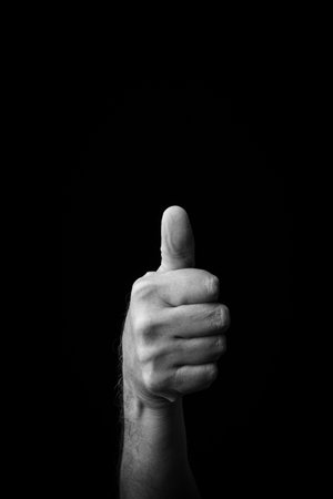 Dramatic black and white  image of a male hand fingerspelling the Japanese sign language letter 'TA' or 'ã', isolated against a dark background with copy space.の写真素材