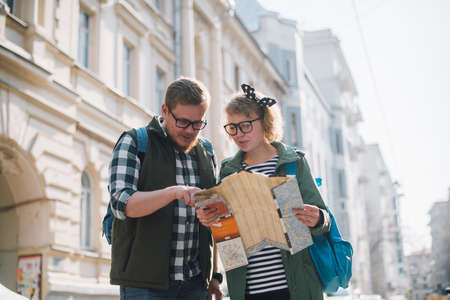 A young couple of tourists are looking for a road with a map in their hands in the city.の写真素材