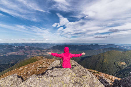 Girl with her hands up on the background of the mountainsの写真素材