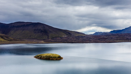 Lake with small island and sky reflection at cloudy day in Iceland