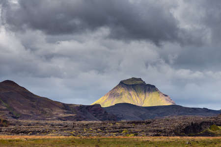 View on a huge mountain and small house in Iceland with dramatic skyの写真素材