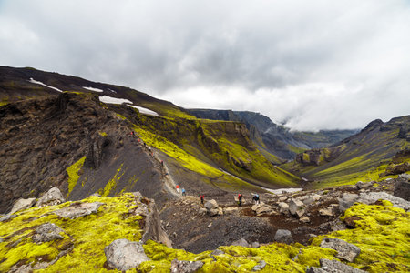 Big tall hill with are climbing up tourists in Iceland