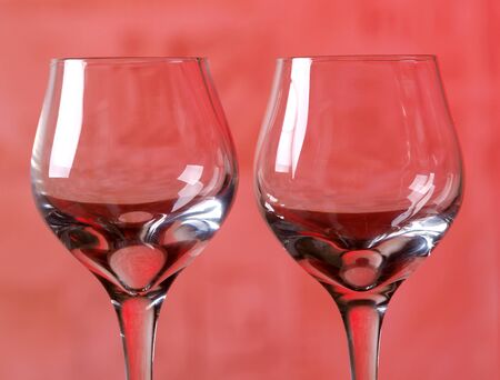 Color photo of a glass of wine glasses in red background        の写真素材