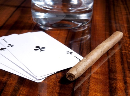 Color photo of cigars, playing cards and cups on a wooden table     の写真素材
