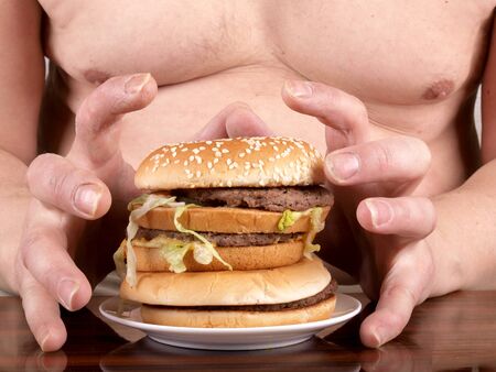 a fat man with a hamburger in his hand     の写真素材