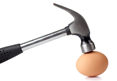 Color photograph of an egg and a metal hammer