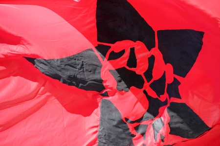 Color photo of a red flag with a black star and fistの写真素材