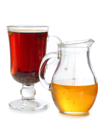 Glass jar with honey and a cup of teaの写真素材