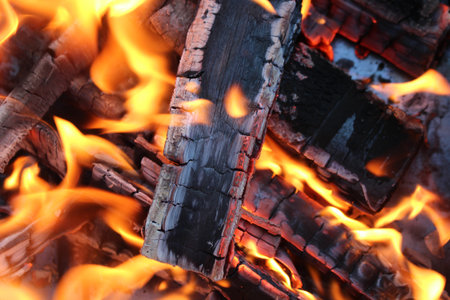 Charred wood and bright flames on dark background