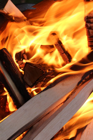 Charred wood and bright flames on dark background