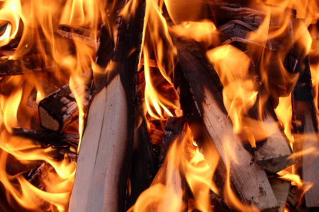 Charred wood and bright flames on dark background