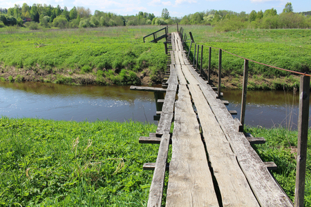 Old wooden bridge over river in summer countrysideの写真素材
