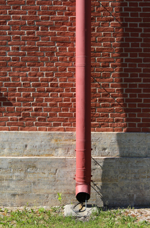 Old metal drainpipe on a stone wallの写真素材