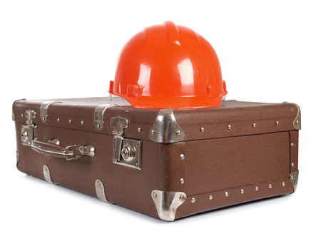 Old suitcase and construction helmets on white backgroundの写真素材