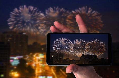 Fireworks in night sky and smartphone in handの写真素材