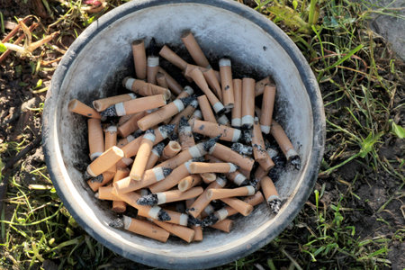 Dirty cigarette butts in a metal bowl