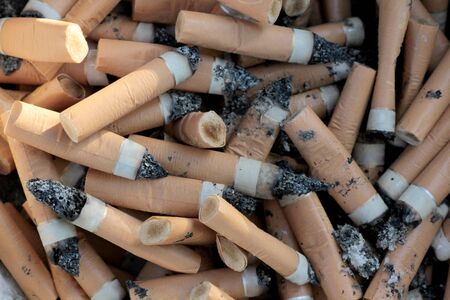 Dirty cigarette butts in a metal bowlの写真素材