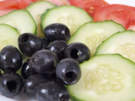 Salad of black olives, tomatoes and cucumbers on a porcelain plateの写真素材