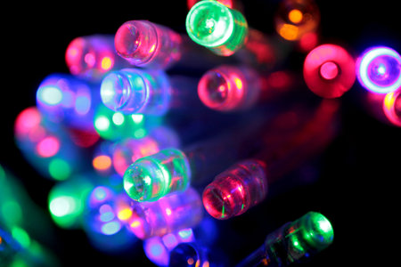 Christmas garland of electric multi-colored light bulbs. Abstract blurred background