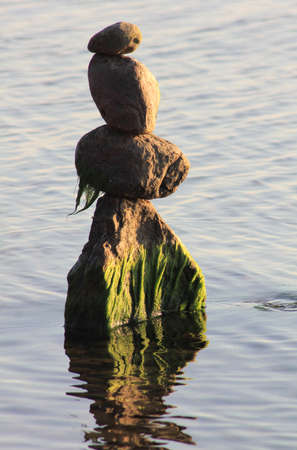Stones in the water are stacked in pyramids. Image on the topic of balance and peace of mindの写真素材