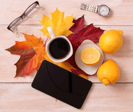 Cup of coffee and autumn maple leaves on an old wooden tableの写真素材