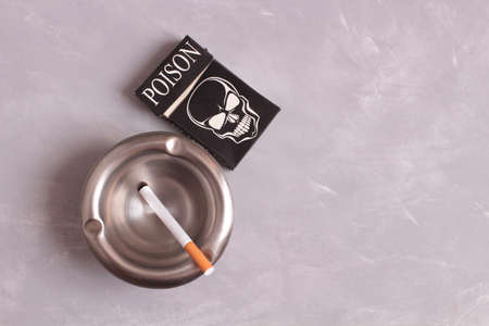 Metal ashtray and pack of cigarettes on stone backgroundの写真素材