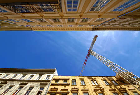 crane between parallel buildings, against the blue skyの写真素材