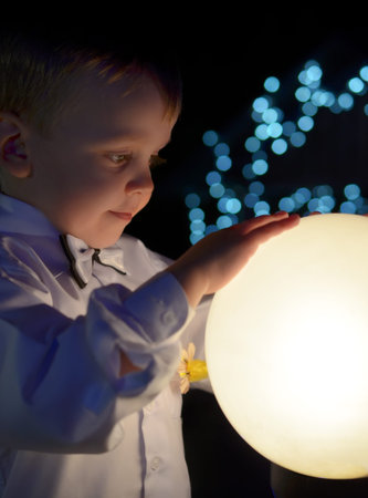 boy in a white shirt holds in hands glowing ball.