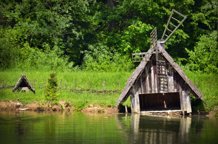 Old wooden house for animals stands in the water of the lake  Against the background of green forest の写真素材