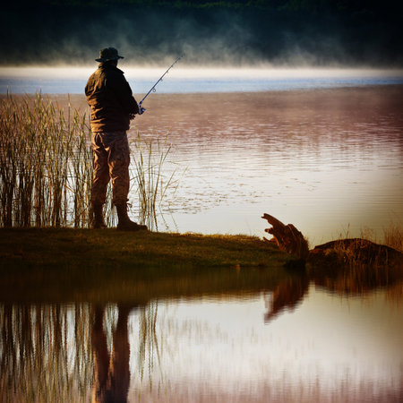 Morning on the lake. A fisherman stands on the shore and catches fish. Reflection in water