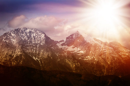 Bright sun rays over the high mountains. Red toning.