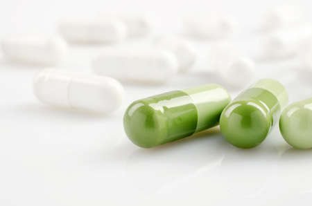 Closeup. Pharmacy theme. Green and white capsules on the white surfaceの写真素材