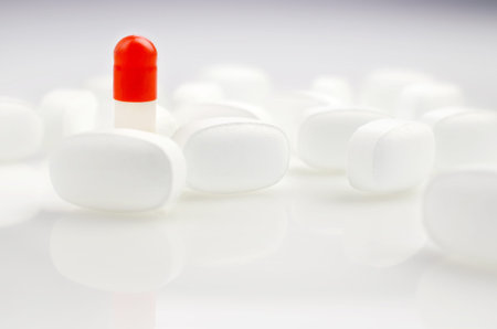 Pharmacy theme. Red and White Isolated Pills and Capsules on the White Surface. Closeup