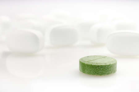 Pharmacy theme. One Green Pill is on the Background of White Pills. Closeupの写真素材