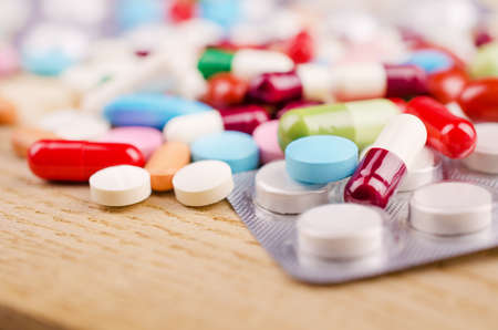Multicolored Capsules and Pills Lying on a Wooden Surface. Closeupの写真素材