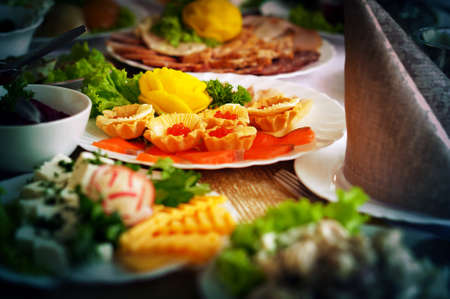 tartlet with red salmon caviar with butter on a festive table near the sausage meats and green lettuceの写真素材