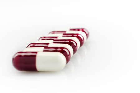 Medical theme. Dark red capsules on a white surface. Closeupの写真素材