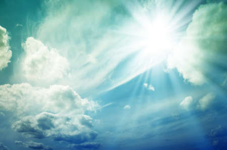 Blue sky with white and gray cumulus clouds. Bright sun with blue raysの写真素材