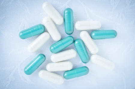 White and blue capsule of medicine on white backgroundの写真素材