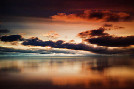 Evening colored sky with dark cumulus clouds over seaの写真素材