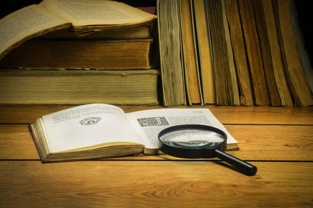 Against the background of old books open book with magnifying glass