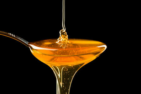 Spoonful of honey on the black backgroundの写真素材
