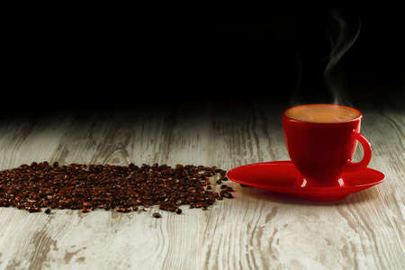 Coffee in the red cup on old boards with coffee beansの写真素材
