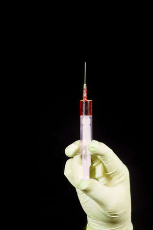 Glove and syringe on the black backgroundの写真素材