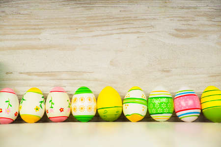Easter concept, colorful Easter eggs arranged in a row on a background of wooden planks in vintage styleの写真素材
