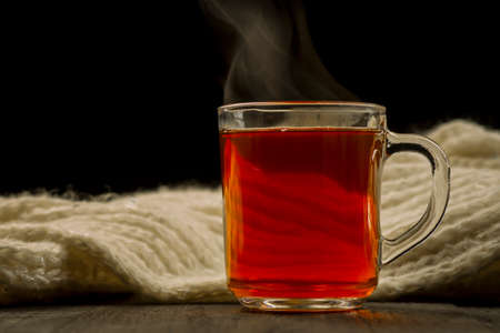 Mug with a scarf with hot tea on a dark backgroundの写真素材