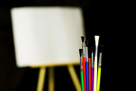 Painting concept, colorful brushes on easel backgroundの写真素材