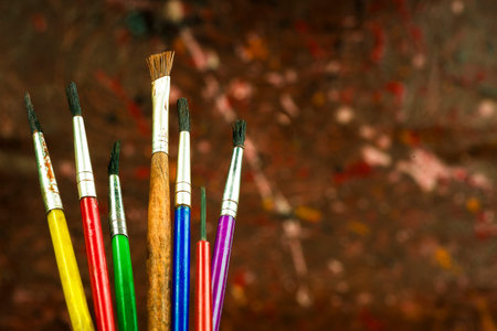 The concept of painting, brushes on a background of multicolored paints applied randomly