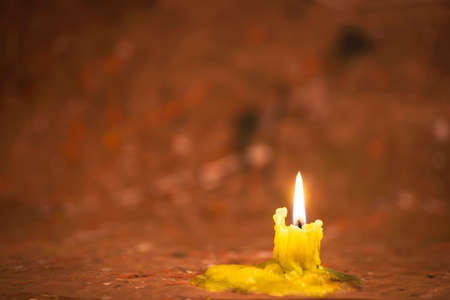 A burned yellow candle against a blurred abstract imageの写真素材