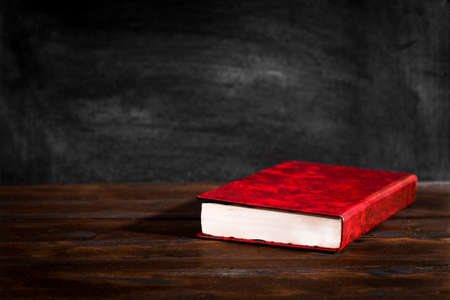 The concept of writing, a red book on old boards on a blackboard backgroundの写真素材